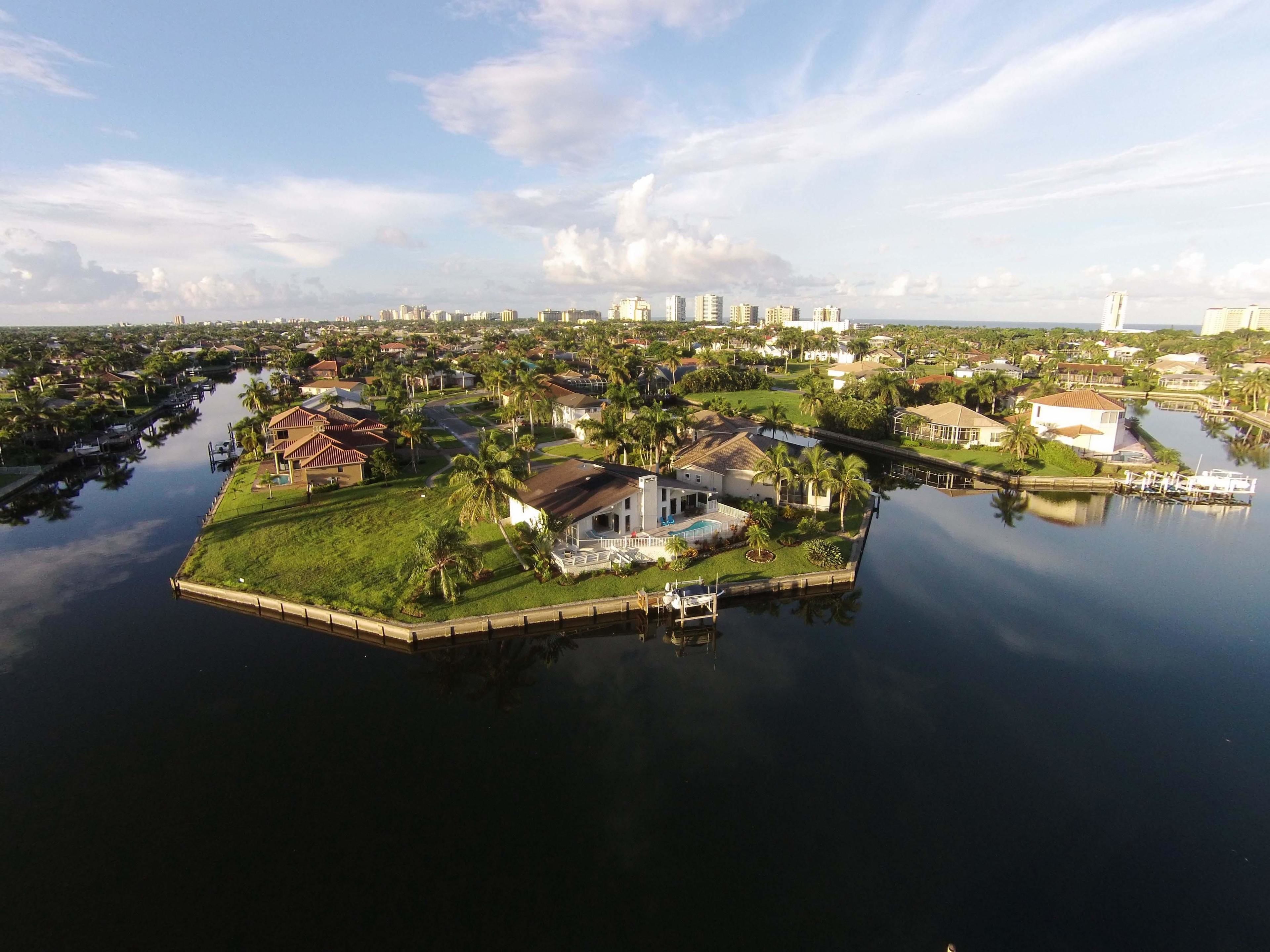 An aerial view of a residential area with houses, a dock, and a calm water body.