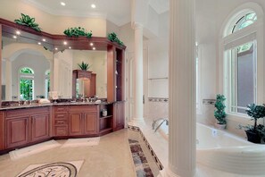 A spacious bathroom with a large bathtub, a vanity with a mirror, and multiple plants. - SPIN509 4 Bedroom Holiday Home by Marco Naples Vacation Homes (Marco Island)