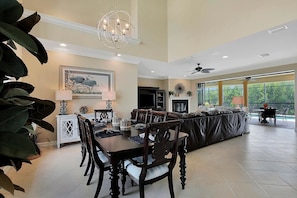 A spacious living area with a dining table, chairs, a sofa, and a fireplace. - SPIN516 5 Bedroom Holiday Home by Marco Naples Vacation Homes (Marco Island)