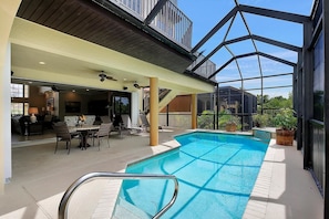 An indoor swimming pool with a glass ceiling, surrounded by lounge chairs and a dining area. - SPIN516 5 Bedroom Holiday Home by Marco Naples Vacation Homes (Marco Island)