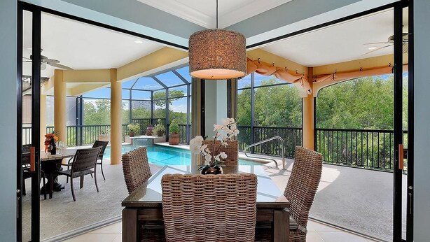 En matplats med flätade stolar, ett glasbord och en hängande lampa.