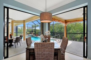 Un coin repas avec des chaises en osier, une table en verre et un luminaire suspendu.