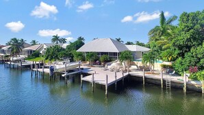 A marina with docked boats, a dock with a lounge area, and houses with sloped roofs. - WH1074 3 Bedroom Holiday Home by Marco Naples Vacation Homes (Marco Island)