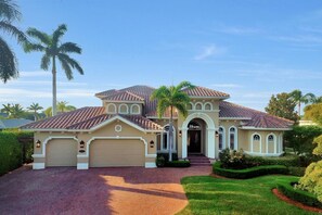 A two-story house with a tiled roof, a garage, and a well-maintained lawn.