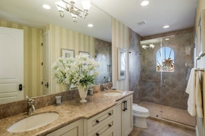 A bathroom with two sinks, a toilet, a shower, and a large mirror.