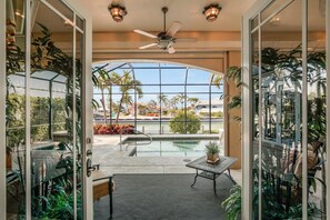 A modern indoor pool area with a glass enclosure, a ceiling fan, and a table with chairs. - WIN1288 4 Bedroom Holiday Home by Marco Naples Vacation Homes (Marco Island)