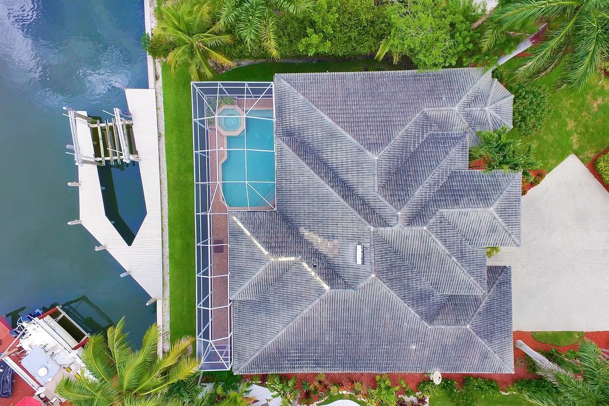 Vista aérea de un resort con piscina, muelle y exuberante vegetación.
