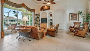 A spacious living room with a fireplace, comfortable seating, and a large window offering a view of the outdoors.