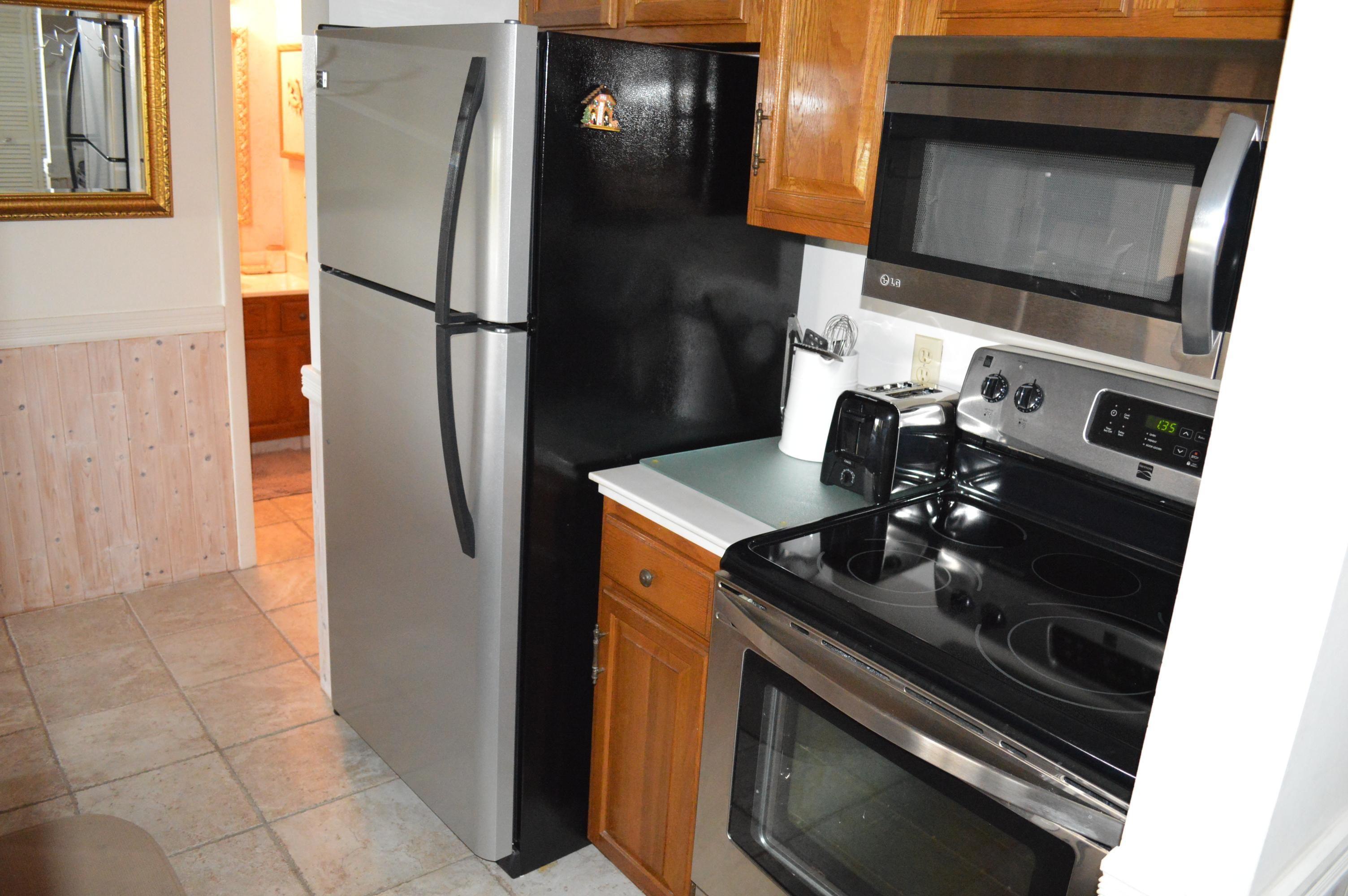 A kitchen with a refrigerator, microwave, stove, and a toaster.