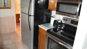 A kitchen with a refrigerator, microwave, stove, and a toaster.