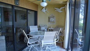 A dining area with a round table and white chairs, a ceiling fan, and decorative wall art.