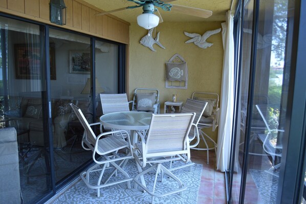 A dining area with a round table and white chairs, a ceiling fan, and decorative wall art.
