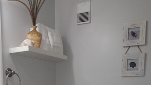 A bathroom with a toilet, sink, towel rack, and decorative items on the wall. - Cove II 127F 2 Bedroom Condo By Midnight Cove II (Siesta Key)