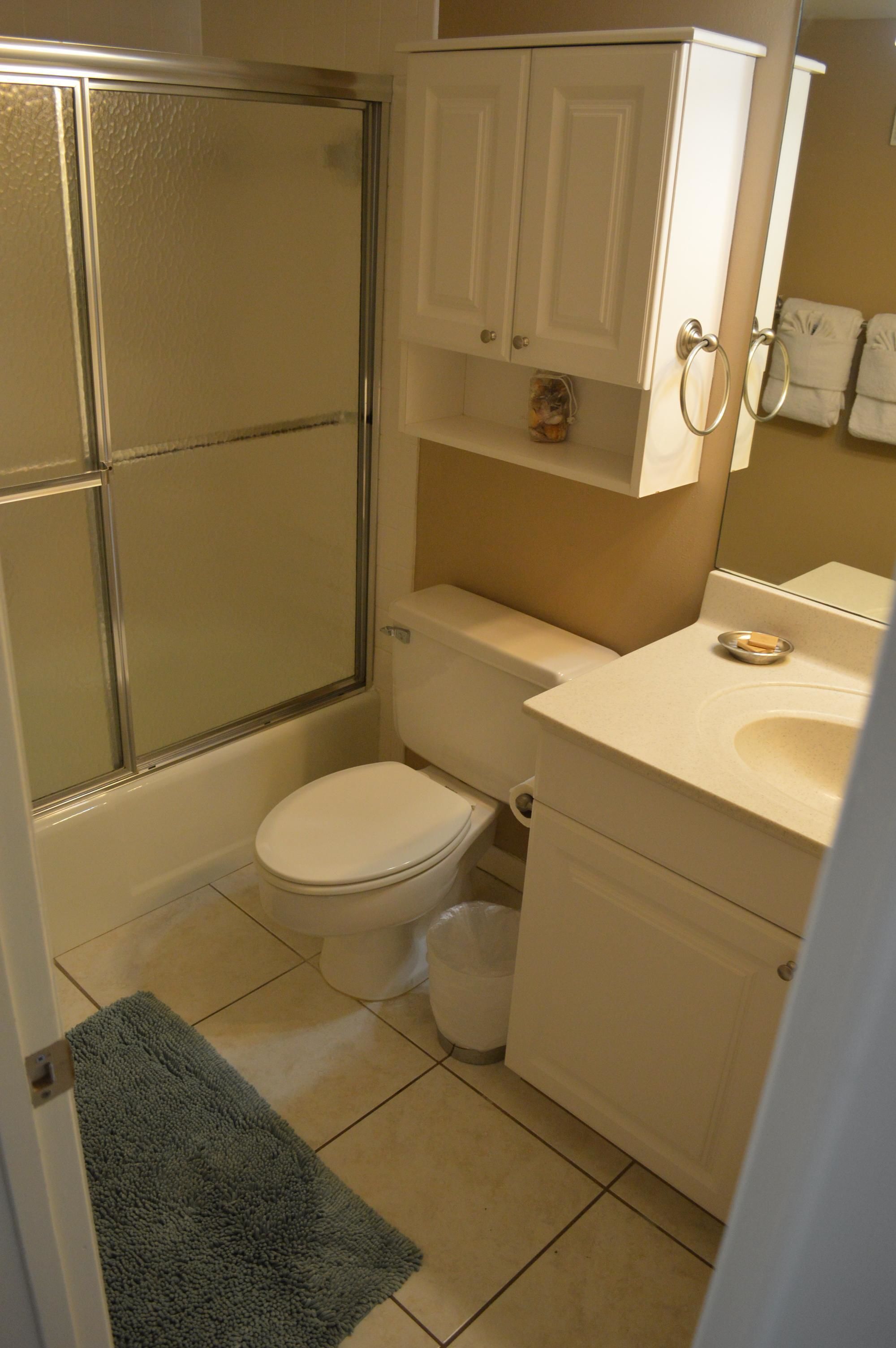 A bathroom with a toilet, sink, and shower enclosure.