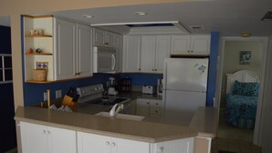 A kitchen with white cabinets, a microwave, a refrigerator, and a sink.
