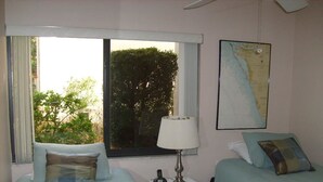 A hotel room with two beds, a window with a view of trees, a lamp, and a framed map on the wall.