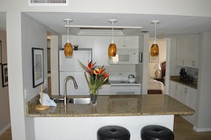 A modern kitchen with granite countertops, stainless steel appliances, and pendant lighting. - Cove II 312F 2 Bedroom Condo By Midnight Cove II (Siesta Key)