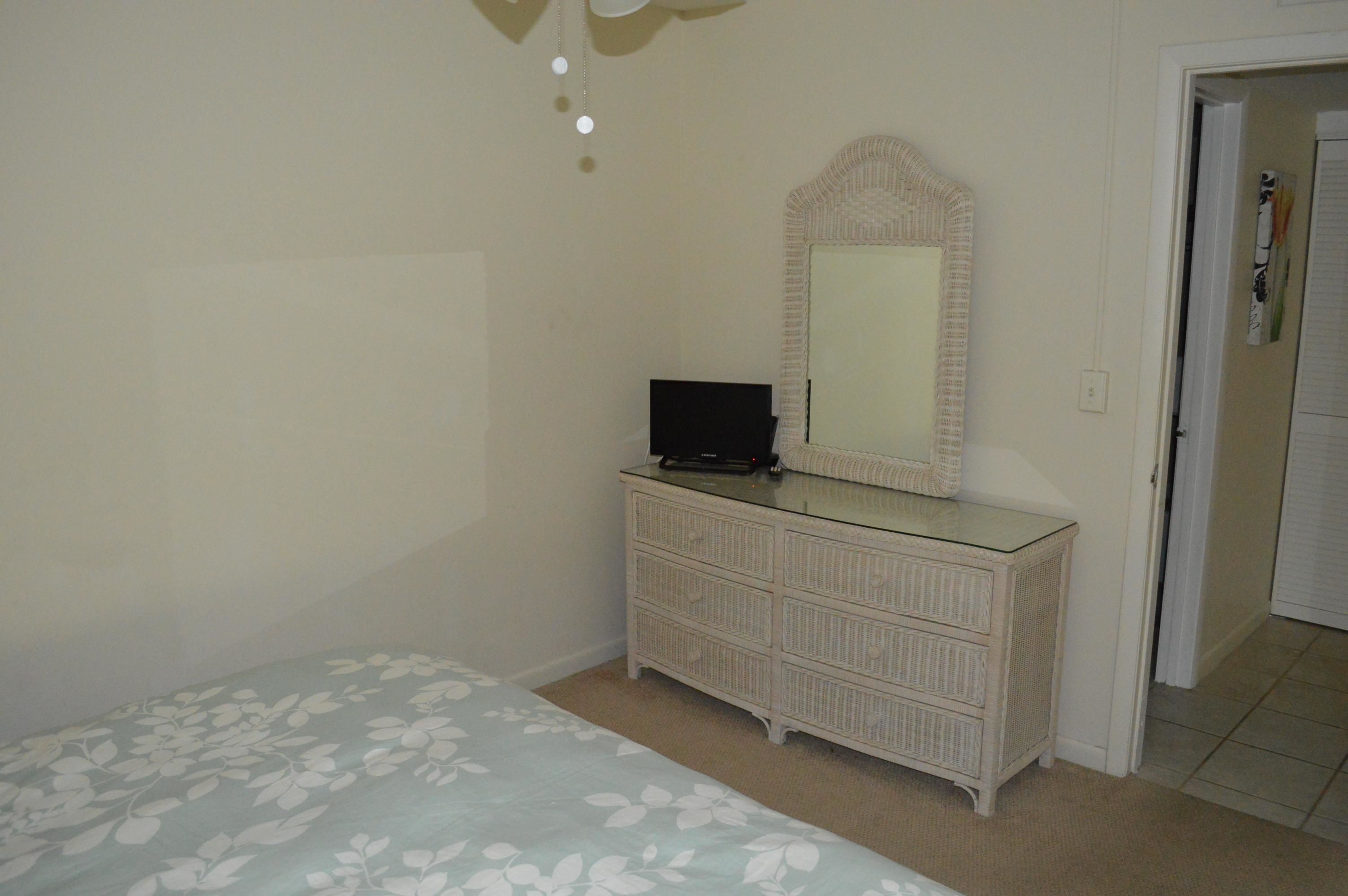 A bedroom with a bed, dresser, mirror, and door.