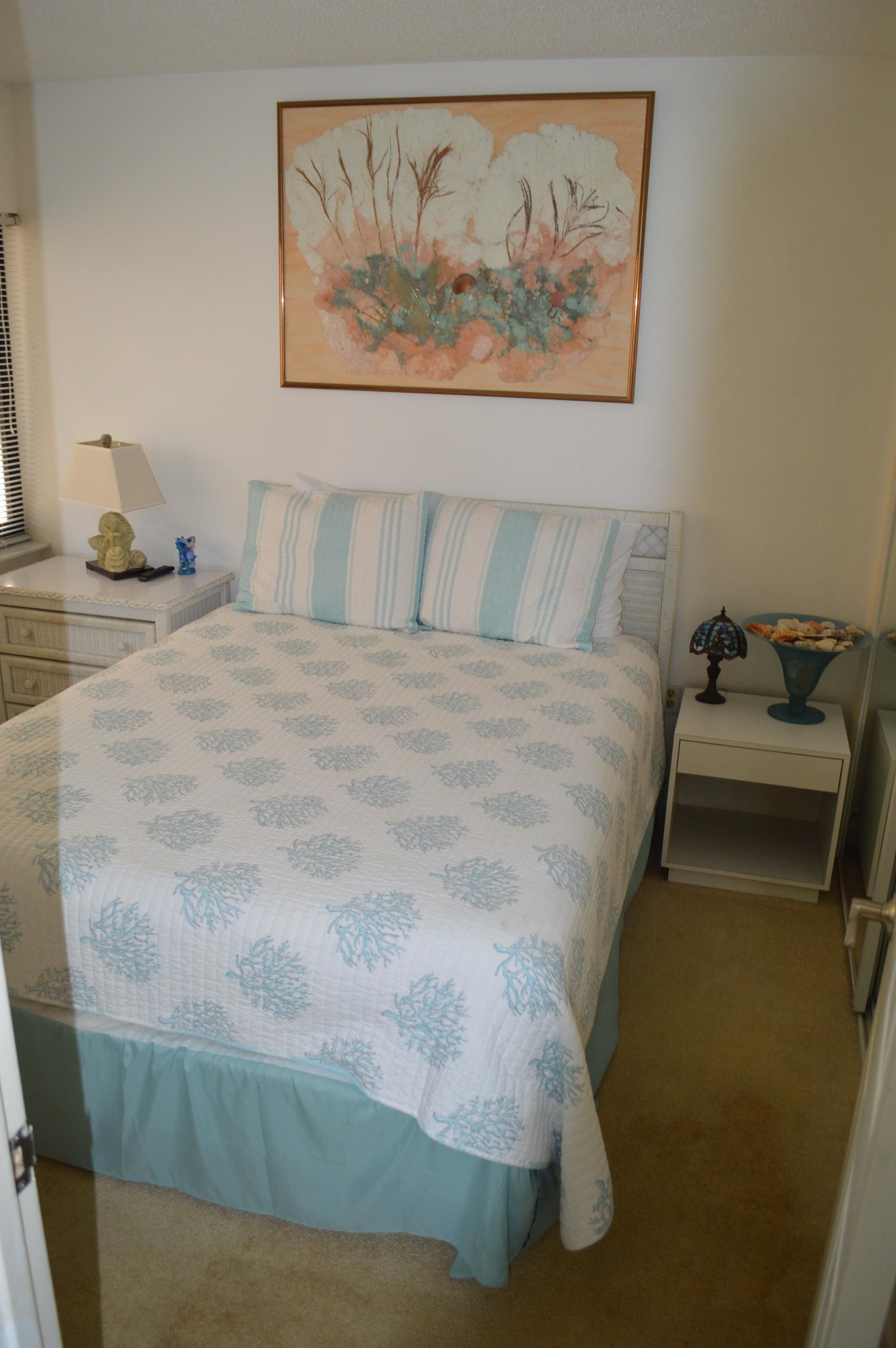 A bedroom with a bed, a nightstand, a lamp, and a wall-mounted painting.