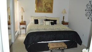 Une chambre à coucher comprenant un lit, deux tables de chevet, un banc, une œuvre d’art accrochée au mur et un élément décoratif mural.
