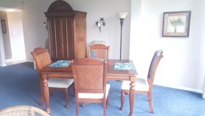 A dining area with a wooden table and four chairs, a cabinet, a floor lamp, and a framed picture on the wall. - Cove II 510F 2 Bedroom Condo By Midnight Cove II (Siesta Key)