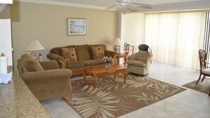 Una sala de estar con un sofá, sillones, una mesa de centro y un ventilador de techo.