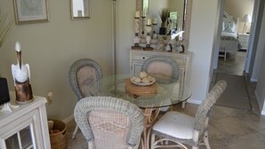 Un coin repas avec des chaises en osier, une table en verre et un élément décoratif central.