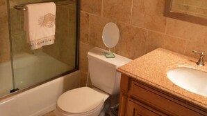 Une salle de bain avec une douche à parois de verre, des toilettes, un lavabo et des meubles en bois.