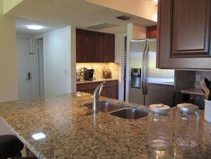 A kitchen with granite countertops, stainless steel appliances, and wooden cabinets. - Cove II 612F 2 Bedroom Condo By Midnight Cove II (Siesta Key)
