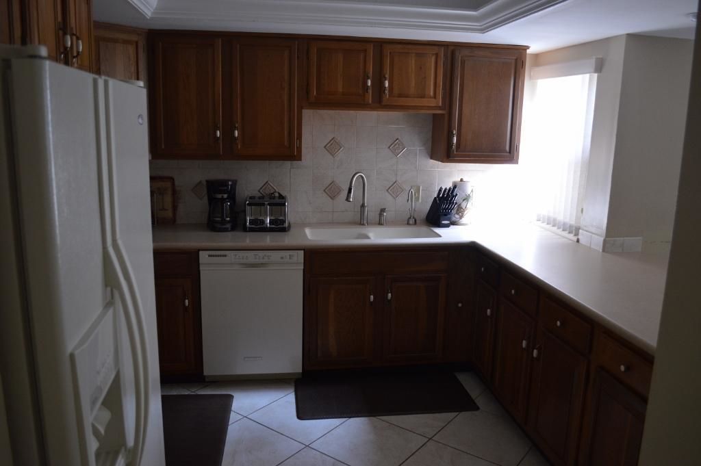 A kitchen with wooden cabinets, a dishwasher, a sink, and a coffee maker.
