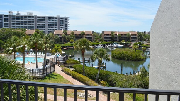 A hotel with a pool, palm trees, and a water body. - Cove II 633F 2 Bedroom Condo By Midnight Cove II (Siesta Key)