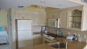 A compact kitchen with a refrigerator, microwave, stove, and a sink. - Cove II 633F 2 Bedroom Condo By Midnight Cove II (Siesta Key)
