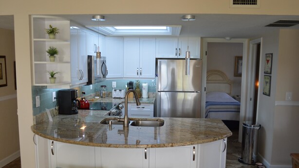 A modern kitchen with a central island, stainless steel appliances, and a skylight. - Cove II 811F 2 Bedroom Condo By Midnight Cove II (Siesta Key)