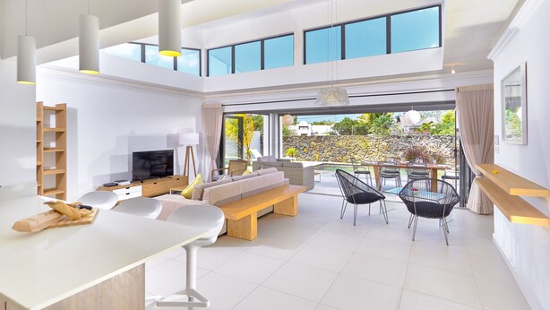 A spacious, modern living area with a large TV, seating, and a dining area.