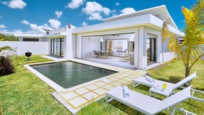 A modern house with a swimming pool, outdoor seating, and a well-maintained lawn.