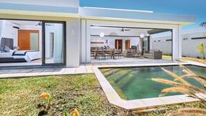 A modern house with a swimming pool, a dining area, and a bedroom with a sliding glass door.