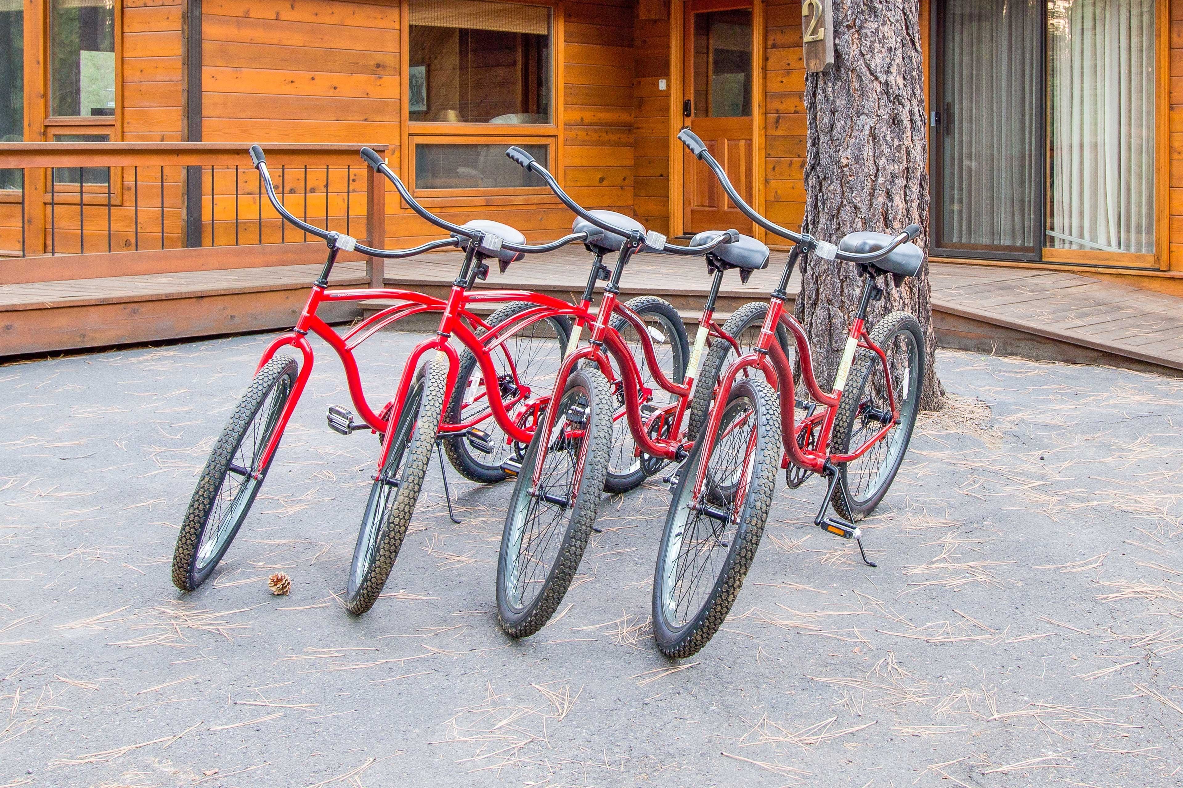 A row of red bicycles parked in front of a wooden building with a number '2' sign.