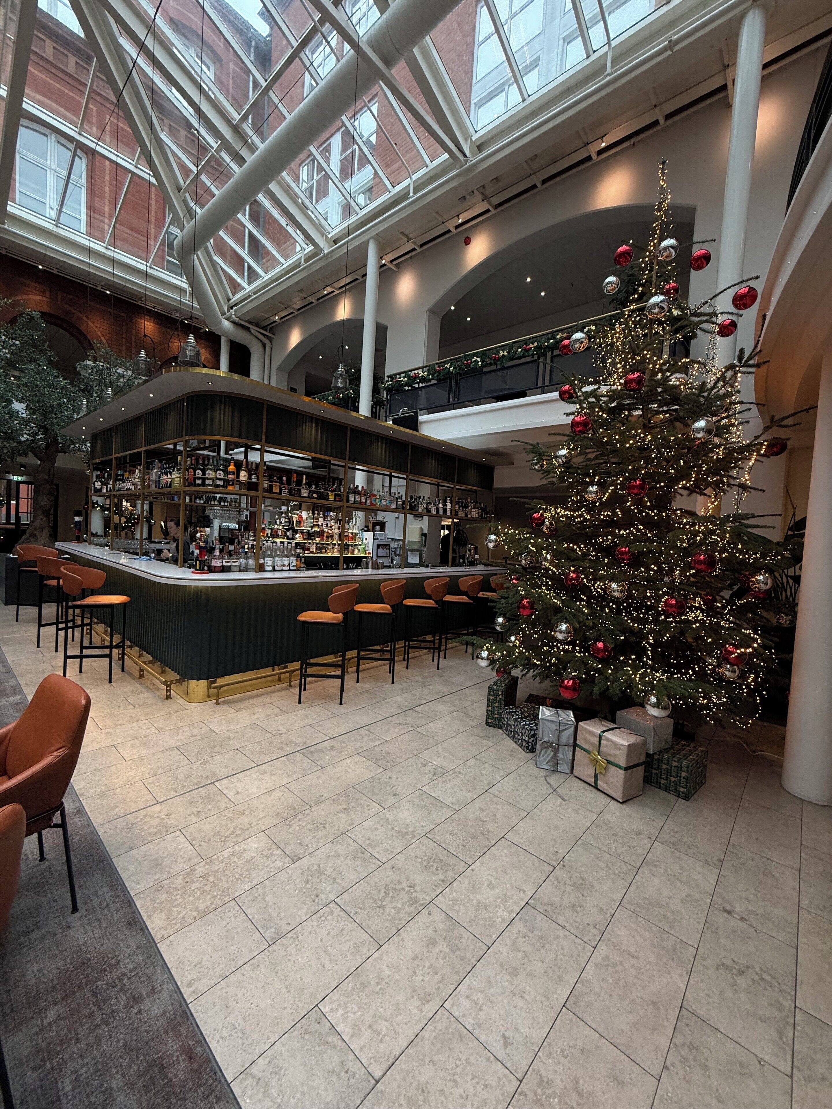 Un espacio interior amplio con barra, asientos y un árbol de Navidad decorado.
