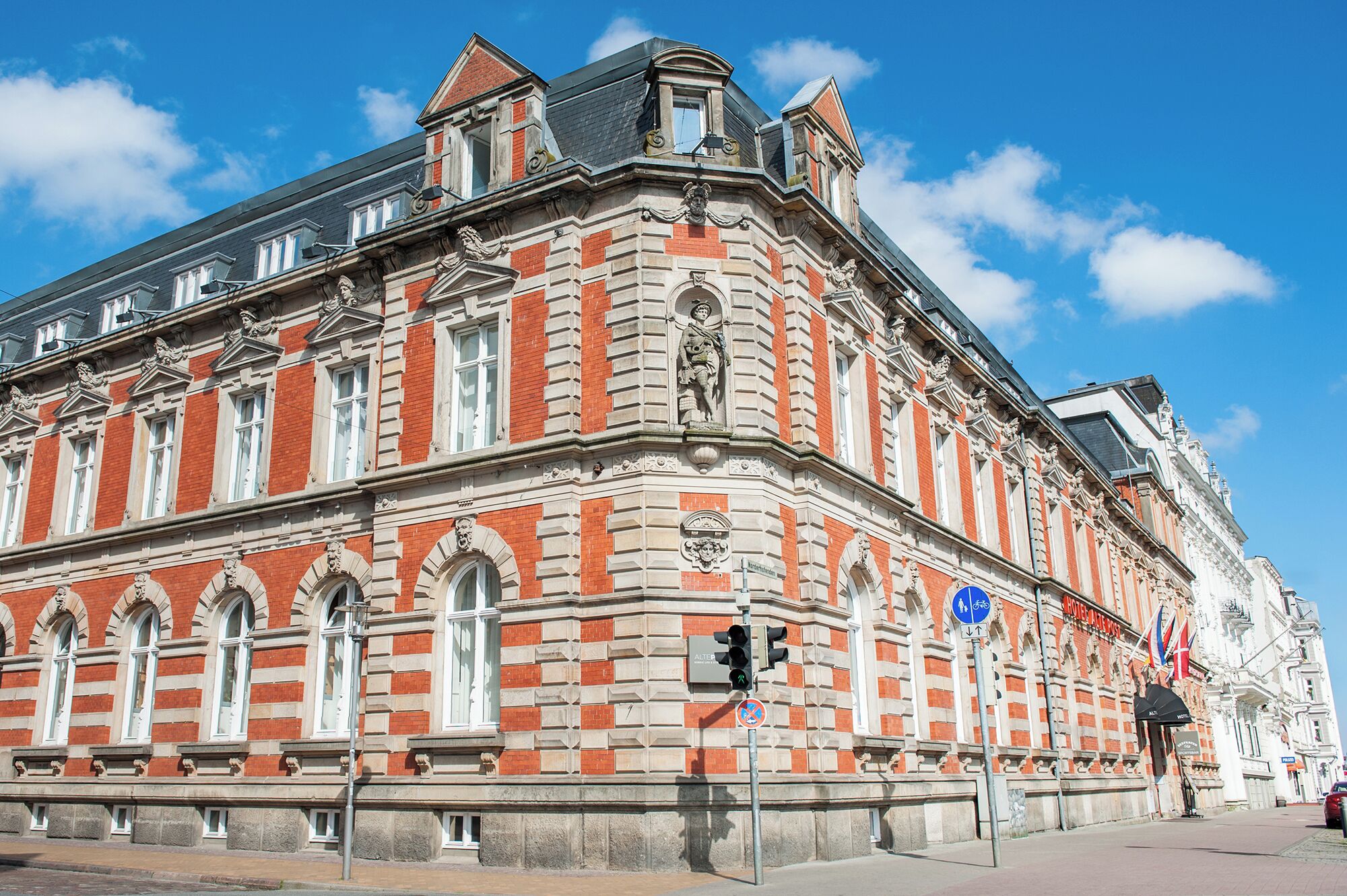 Un edificio histórico con arquitectura clásica, que presenta una entrada destacada en esquina y un gran ventanal arqueado.