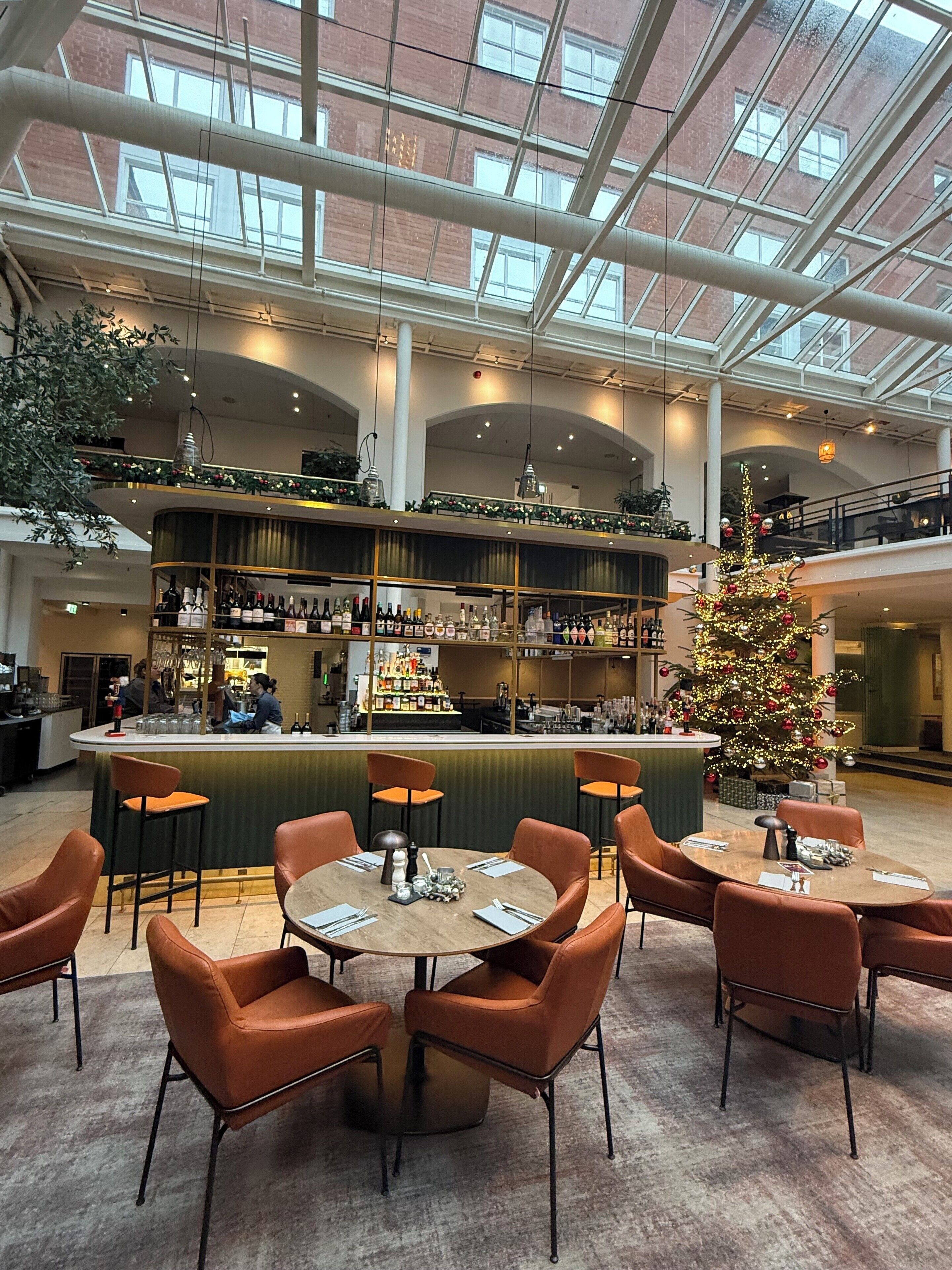 A spacious indoor area with a high ceiling, a bar with a green counter, and a Christmas tree.