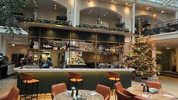 A spacious indoor area with a high ceiling, a bar with a green counter, and a Christmas tree.