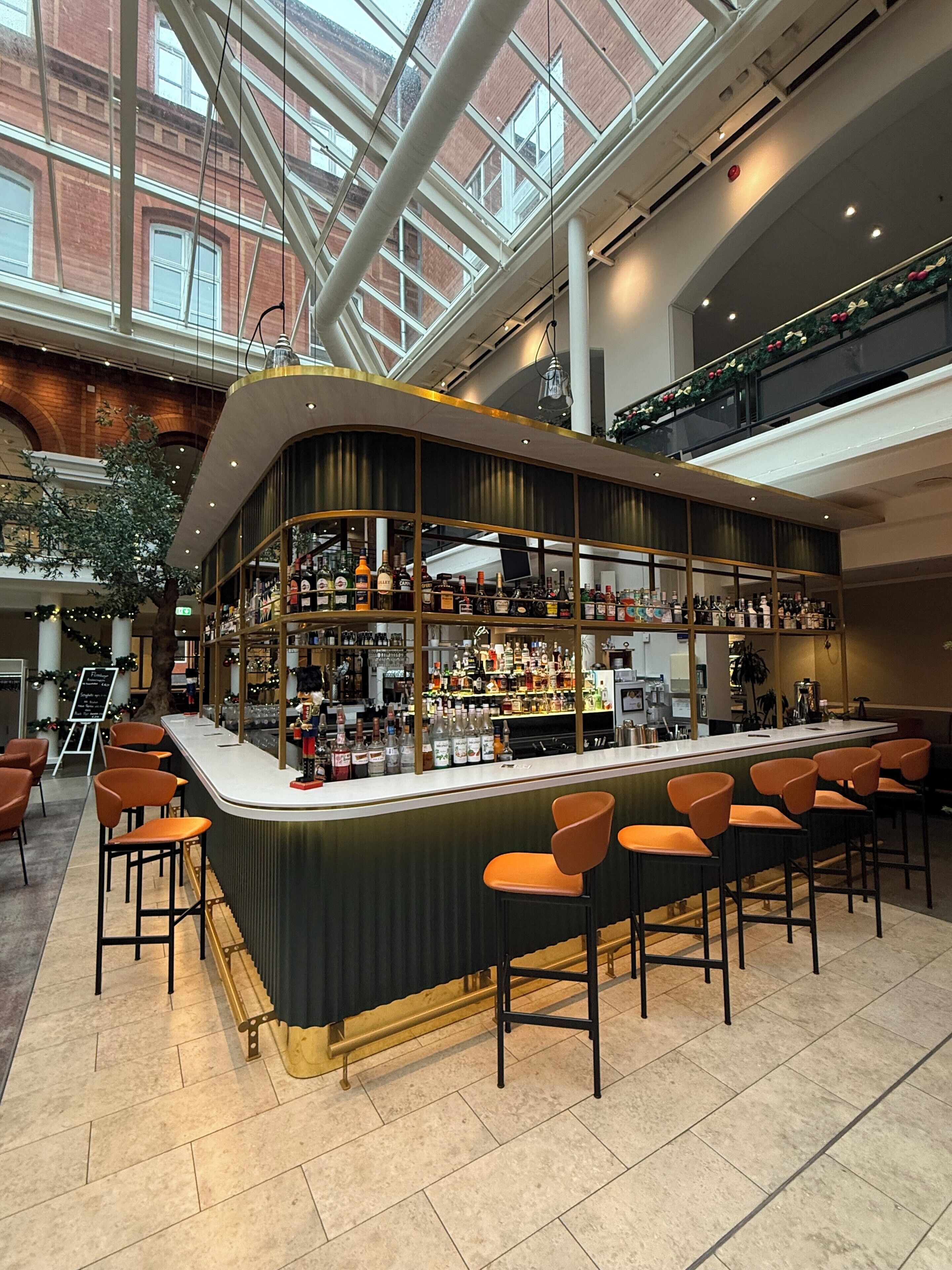A bar area with a curved counter, multiple seating options, and a view of the building's interior architecture.