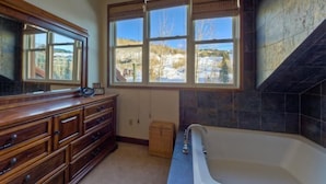 Un bagno con una grande finestra, un mobile bagno in legno e una vasca da bagno.