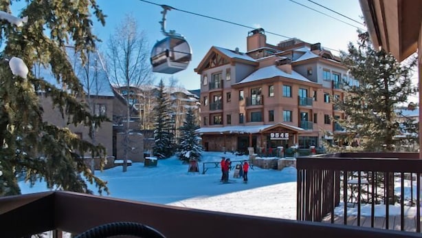 Area esterna innevata con una seggiovia, un edificio con numerosi balconi e un cartello con la scritta "855".