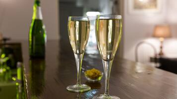 Two champagne flutes on a wooden table with a green bottle in the background.
