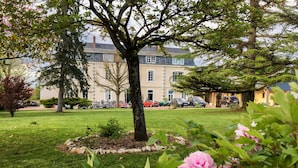 A tree-lined courtyard with a building in the background. - Le Haut des Lys (Villandry)