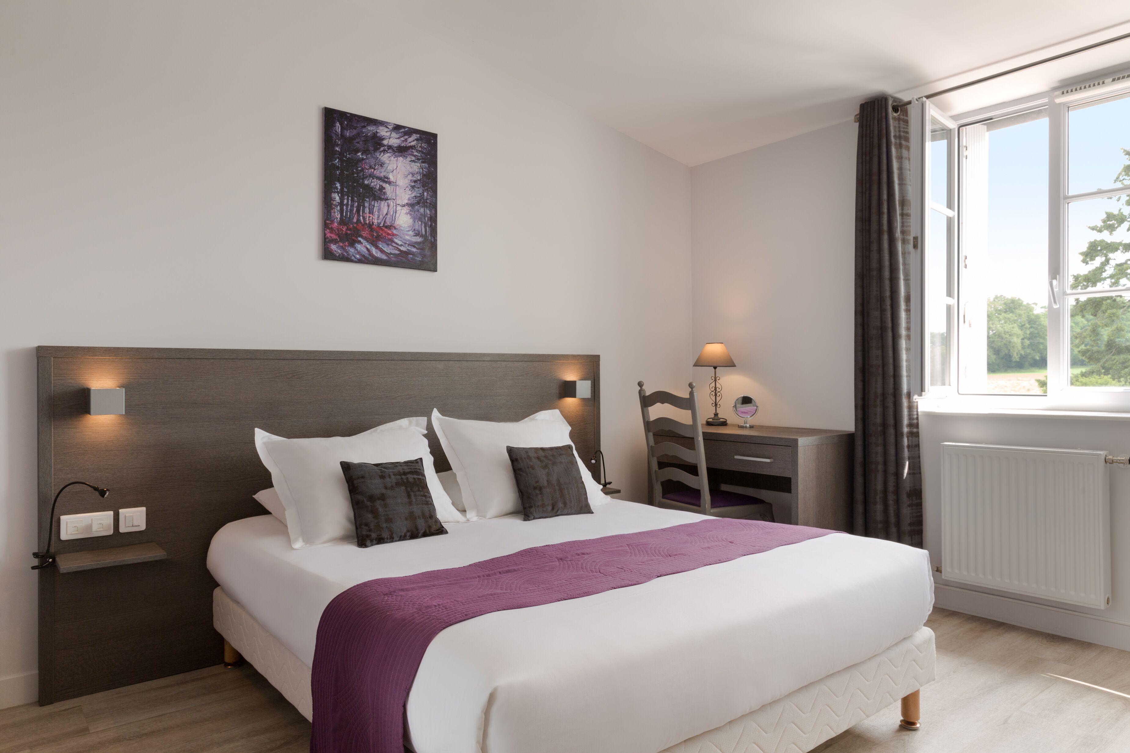 A neatly arranged bedroom with a large bed, bedside lamps, a nightstand, and a window with curtains.