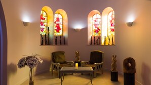 A room with three arched windows, a table with a candle, two chairs, and a vase of flowers. - Le Haut des Lys (Villandry)