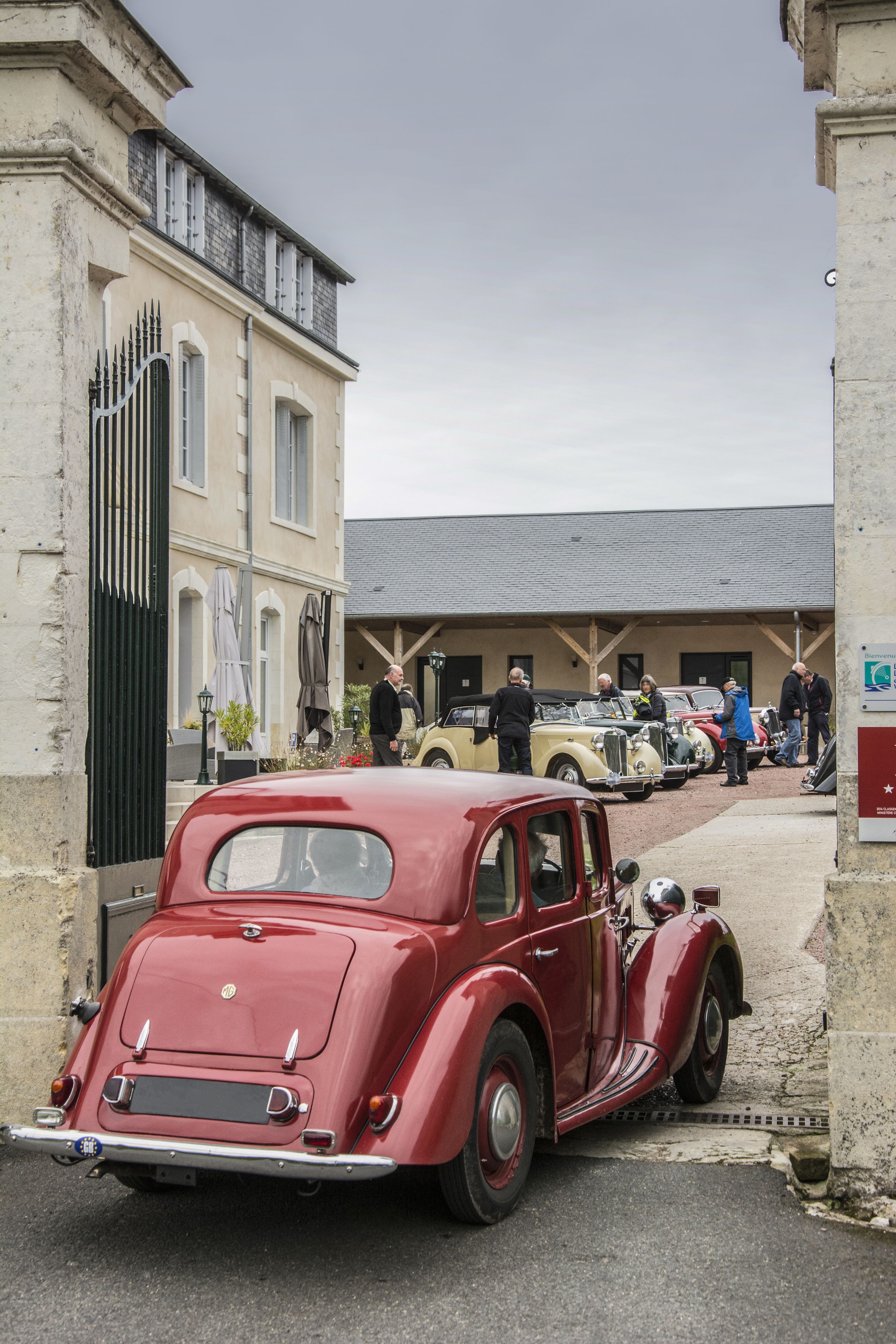 Een klassieke rode auto geparkeerd voor een gebouw met een stijlvolle, traditionele architectuur.