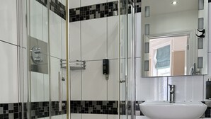 A modern bathroom with a glass-enclosed shower, a white sink, and a toilet.